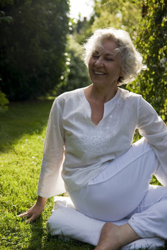 lächelnde Seniorin macht Yoga in der Natur