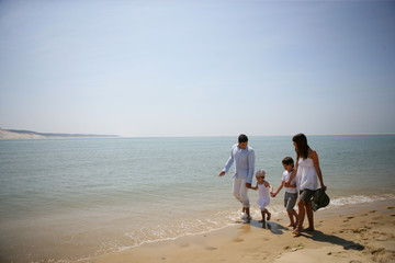 Fototapeta na wymiar Homme et femme marchant au bord de la mer avec des enfants
