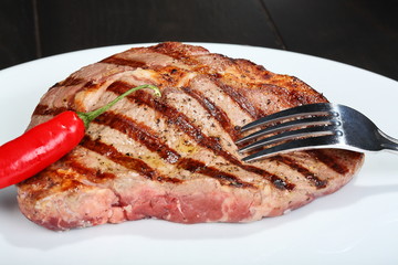 Juicy beef steak, red hot pepper and fork