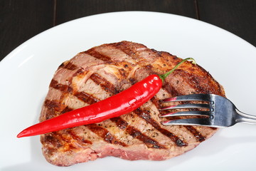 Juicy beef steak, red hot pepper and fork