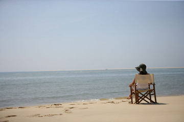 Femme assise sur une chaise au bord de la mer