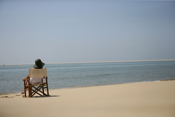 Fototapeta na wymiar Femme assise sur une chaise au bord de la mer