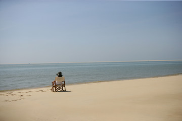 Femme assise sur une chaise au bord de la mer