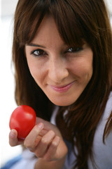 Portrait d'une femme souriante avec une tomate à la main