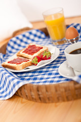 Homemade breakfast on wicker tray with checked teacloth