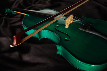 Green violin and a bow on black silk