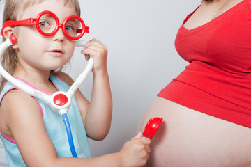 Little daughter with pregnant mother listen stomach