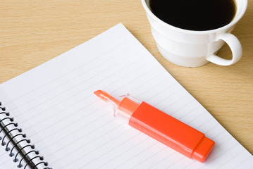 Spiral notebook with cup of coffee and highlighter