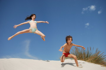 enfants sautant dans des dunes de sable blanc