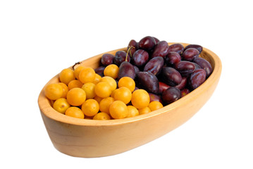 Two kinds of plums in a wooden bowl