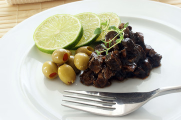 marinated cuttlefish with olive and lime on a white plate