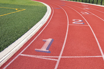 Lanes of a red race track with numbers and green football field