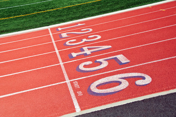 Lanes of a red race track with numbers and green football field