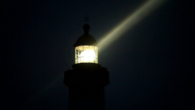 illuminated spinning lighthouse closeup with light beams