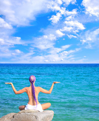 Beautiful girl meditating on the beach