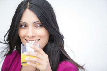 femme souriante avec un verre de jus d'orange à la main