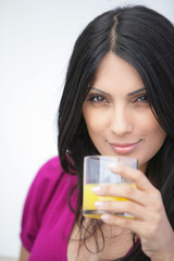 femme souriante avec un verre de jus d'orange à la main