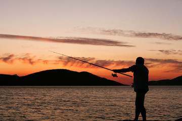 Silhouette of a man fishing in a sunset
