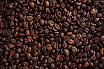 Draufsicht auf eine Menge an dunklem glänzendem Kaffee, geröstete Kaffeebohnen Hintergrundmuster Querformat