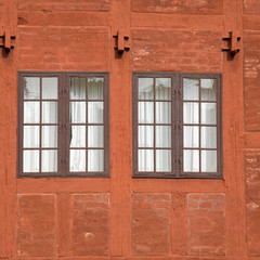 two old multipanel windows in a terracotta colored brick and woo