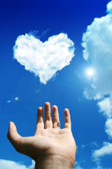 hand above a heart cloud on the sky
