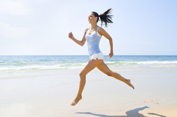 Junge sportliche Frau rennt am Strand