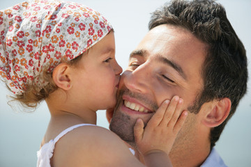 Portrait d'une petite fille embrassant un homme sur la joue
