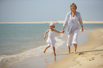 Femme se promenant au bord de la mer avec une petite fille