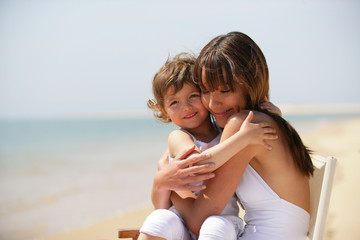 petite fille assise sur les genoux d'une femme au bord de la mer