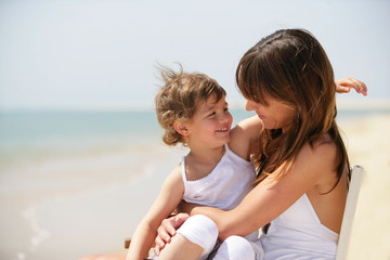 petite fille assise sur les genoux d'une femme au bord de la mer