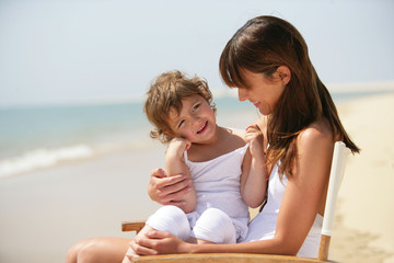 petite fille assise sur les genoux d'une femme au bord de la mer