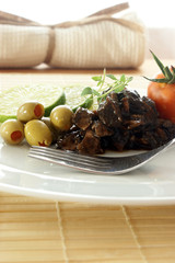 marinated cuttlefish with olive and tomato on a white plate