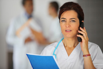 femme en blouse blanche au téléphone en lisant un document