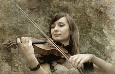 Beautiful female violinist playing violin on the grunge backgrou