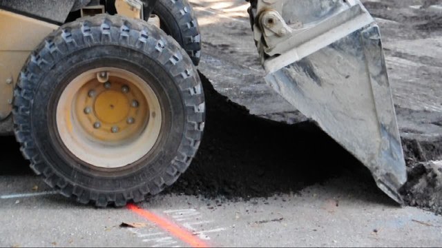 Skid steer loader moving dirt on the street