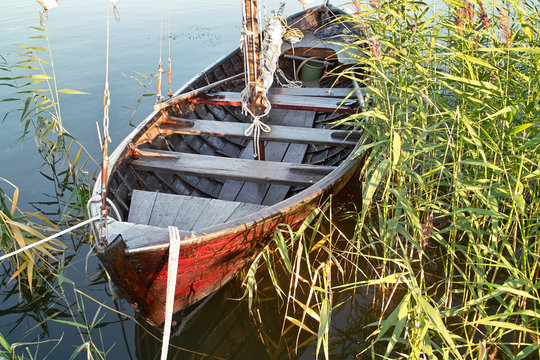 Old wooden sailboat tied up in the reeds