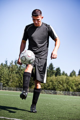 Hispanic soccer or football player kicking a ball