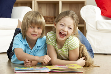 Fototapeta premium Two Young Children Reading Book at Home