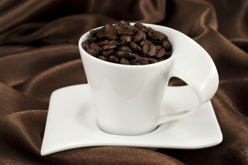 Cup of cofee beans on brown satin