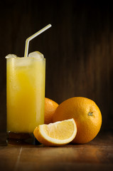 Oranges and orange juice in a glass on a dark background