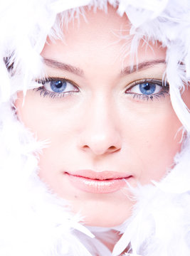 young woman with blue eyes and white boa over her face