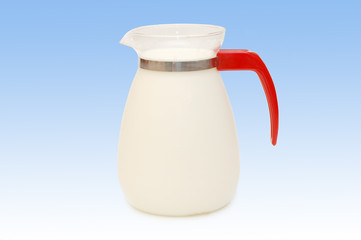 Glass jug of milk on blue background