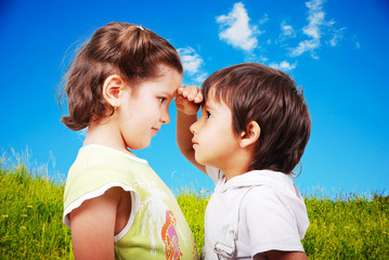 Two cute children, male and female, comparing their height