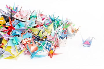 A paper crane standing out from a pile of paper cranes