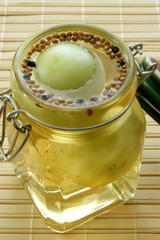 green tomato in a jar with vinegar and spice