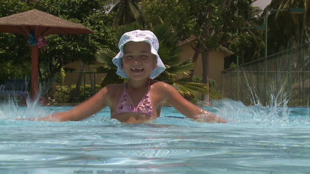 Little girl having fun splashing water in a pool