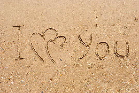 inscription on sand I  love you and two connected hearts