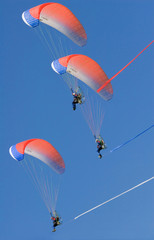 Three motor powered paragliders in blue sky