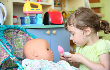 Obraz na płótnie Canvas little girl feeds doll