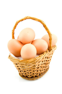 cane basket with chicken eggs over white background